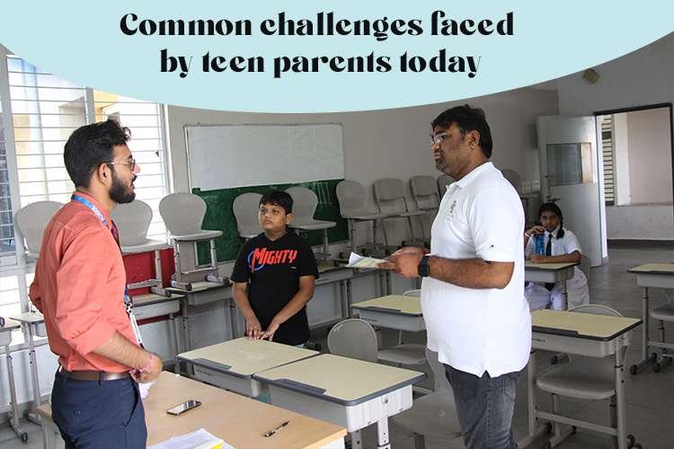 A parents of teens talking to a teacher in a classroom