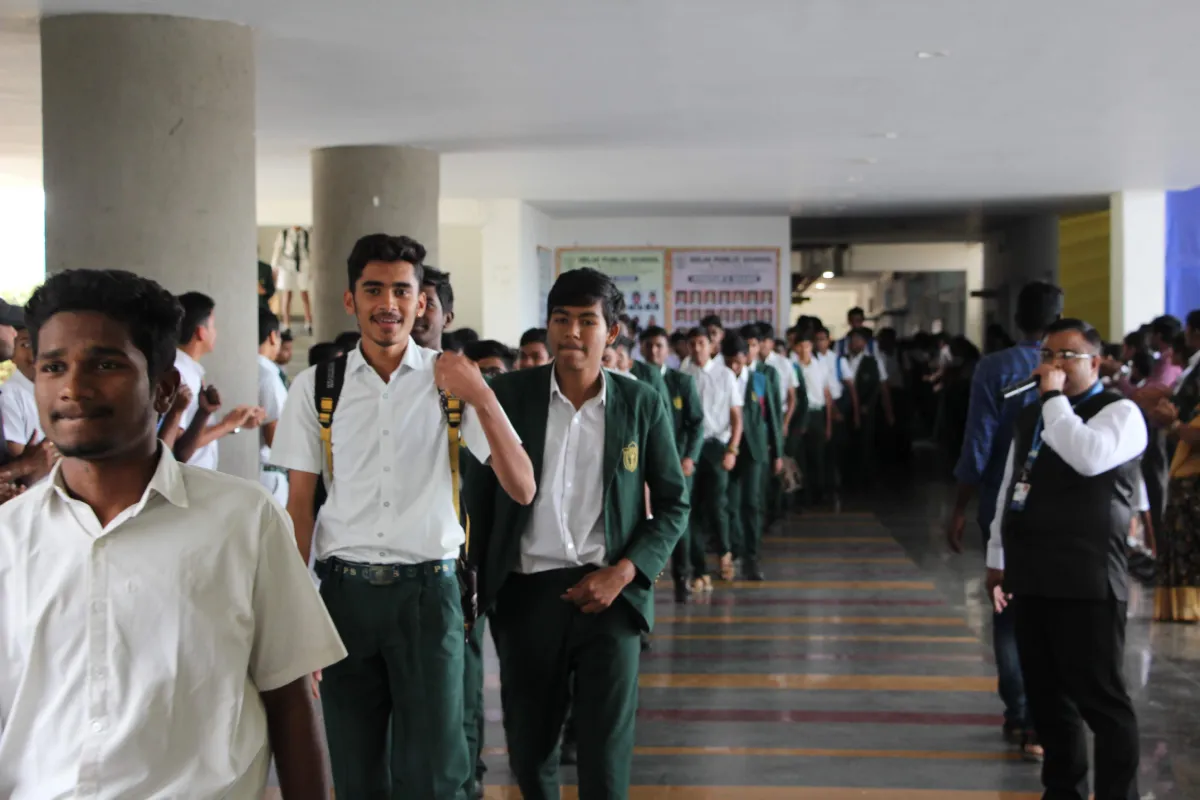 DPS Warangal students standing in a queue with their bags in the school corridor.