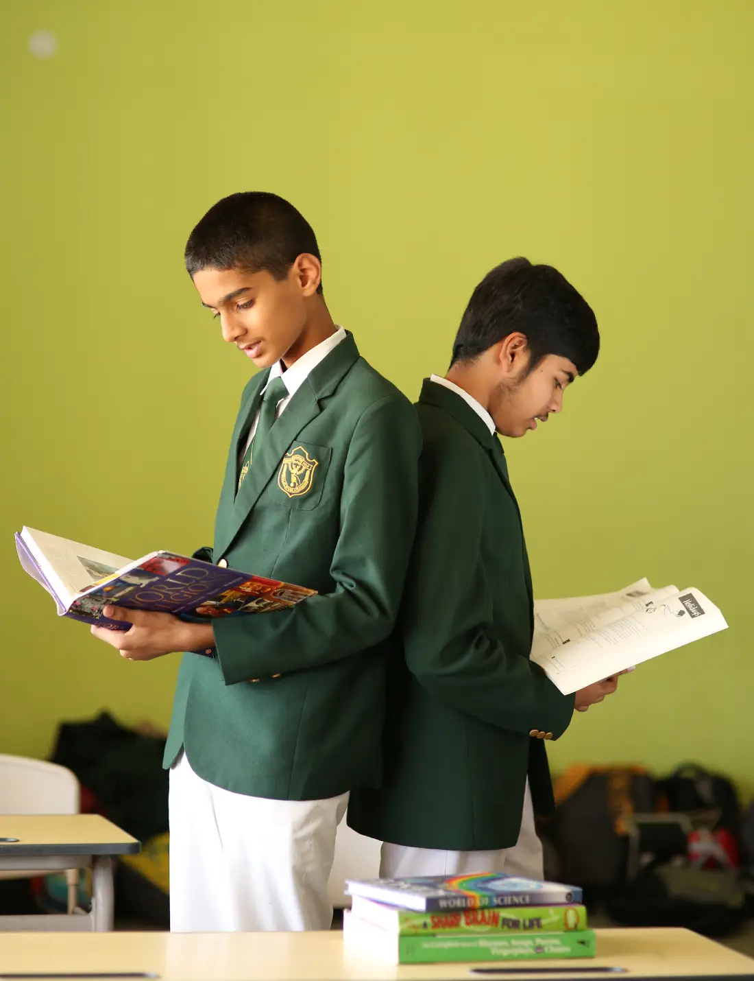 Two boys standing with a book in their hands in a white-green school uniform.