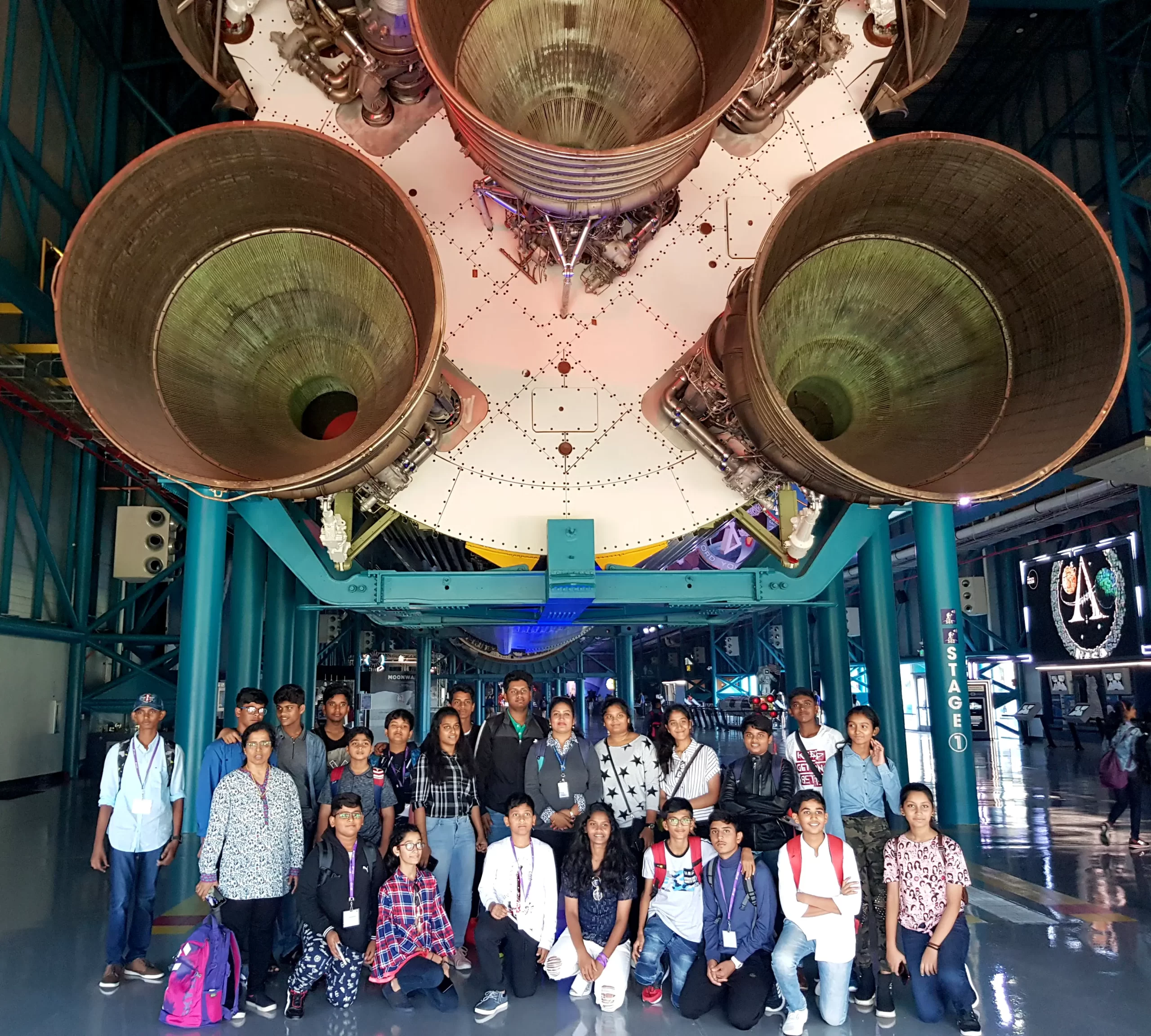 Students clicking picture standing in front of platform having rocket during visit to NASA.