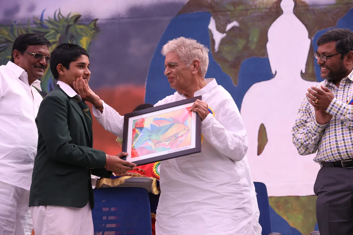 Student in school uniform offering a beautiful painting of fish to the guests at DPS, Warangal.