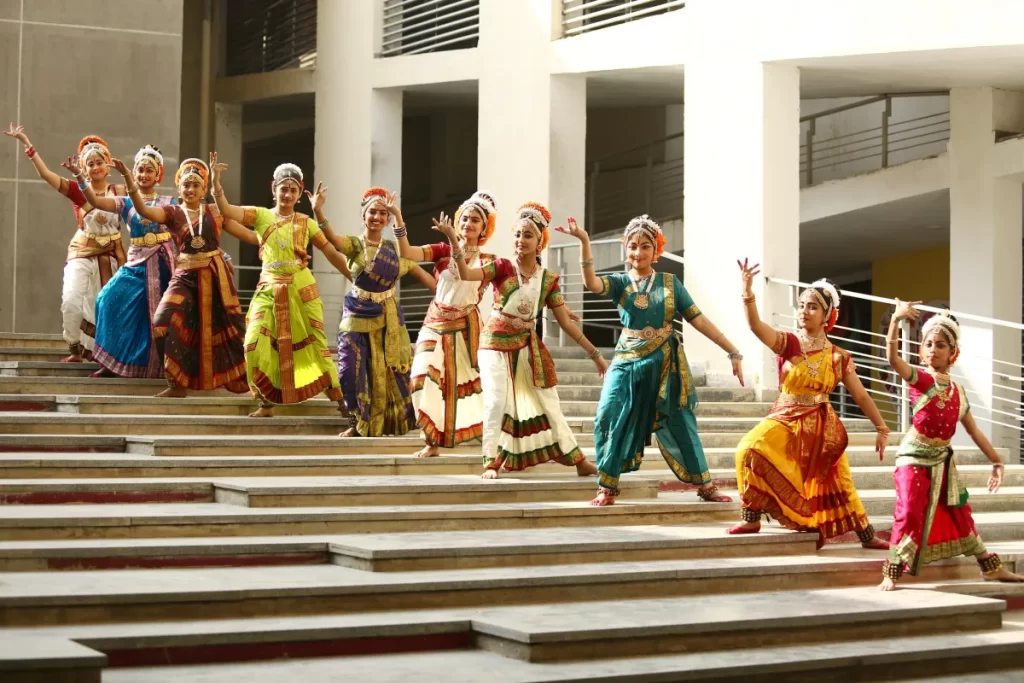Students standing on the stairs in a cultural dress in Bharatnatyam pose.