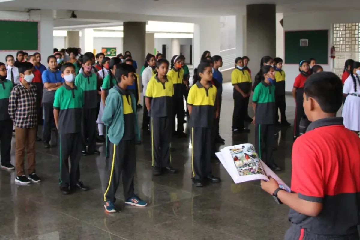 At DPS Warangal,students standing in activity hall in house dress and reading books.