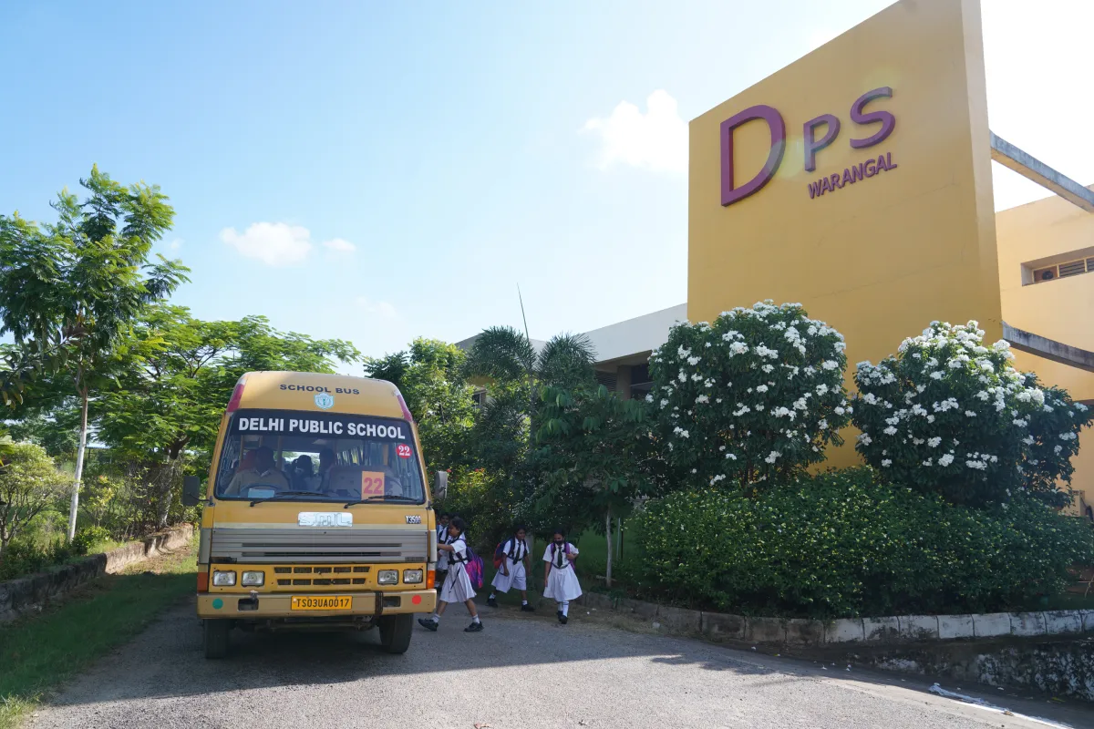 Students are getting onto the yellow color DPS Warangal school bus.