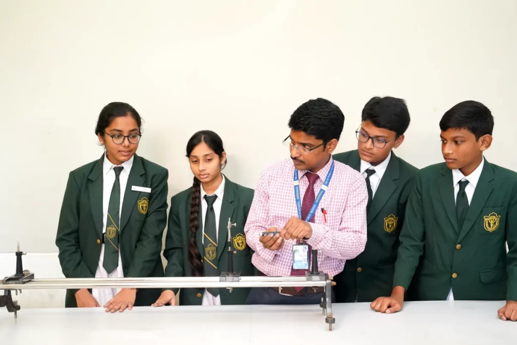 Teacher in a pink shirt showing the physics experiment to the students of DPS Warangal,