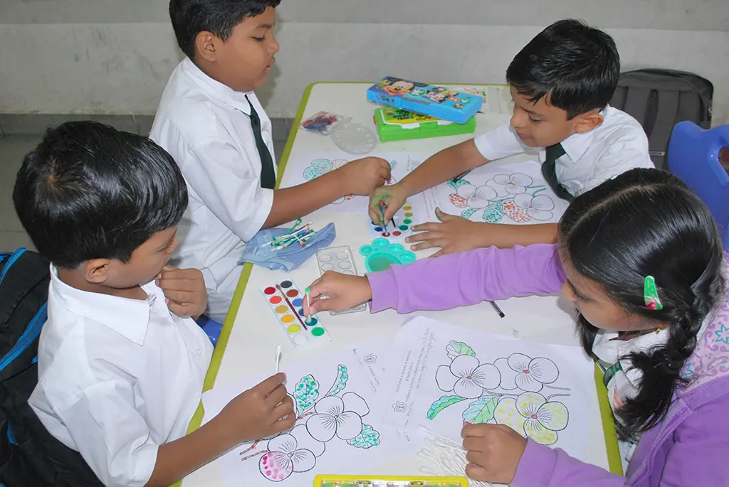 Students sitting together and coloring on the sheet.