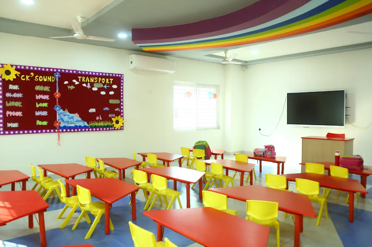 Classroom view of DPS Primary School, Hanamkonda, Warangal having clean red and yellow coloured chairs, bulletin board and E-board.
