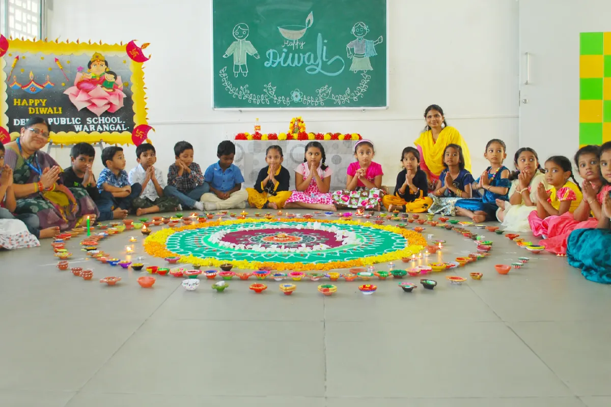Students sitting around the beautiful rangoli, celebrating Diwali with their friends and teachers in the class.