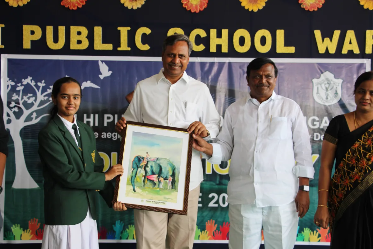 Student in school uniform offering a beautiful painting of elephant to the guests at DPS, Warangal.