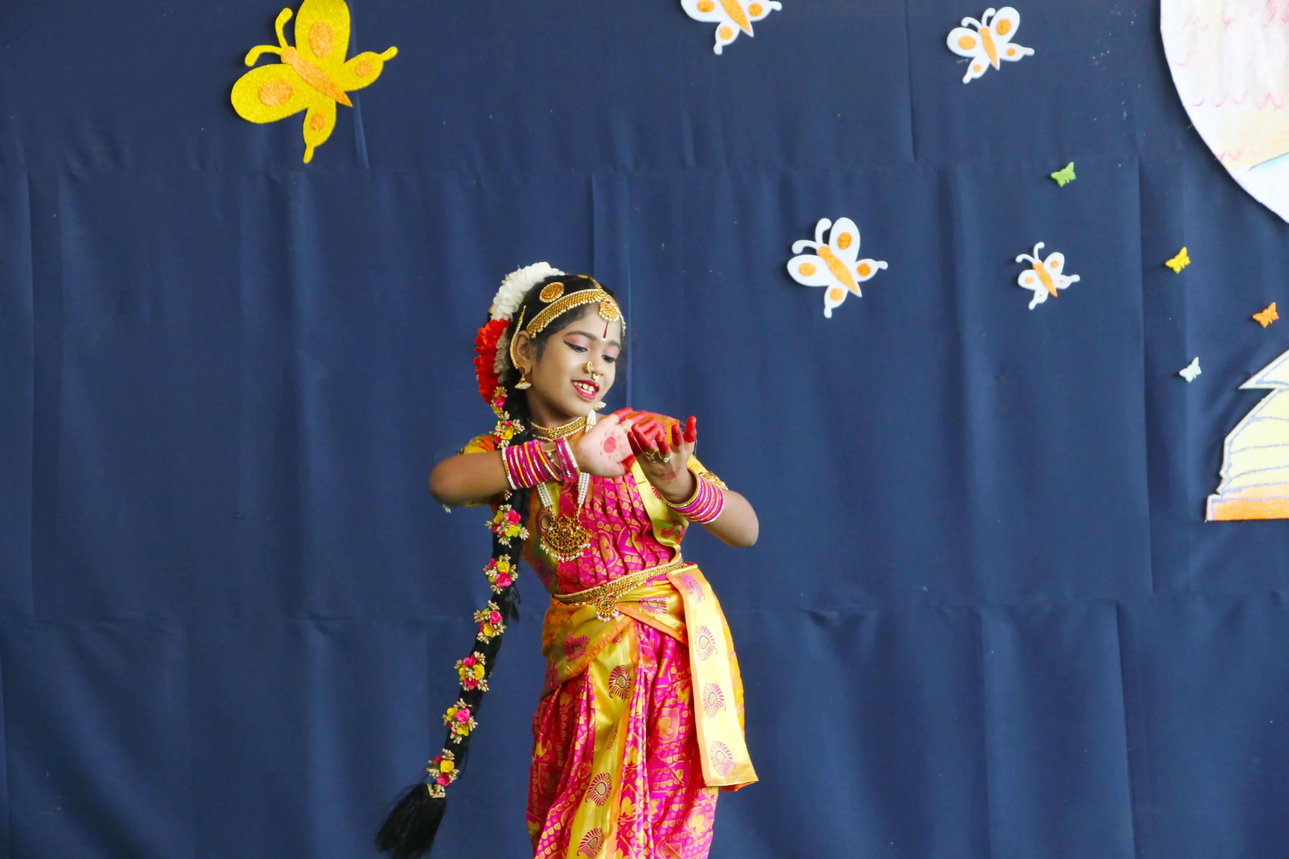 Student of DPS, Warangal dressed in beautiful traditional attire with henna on hand displaying Bharatnatym steps.