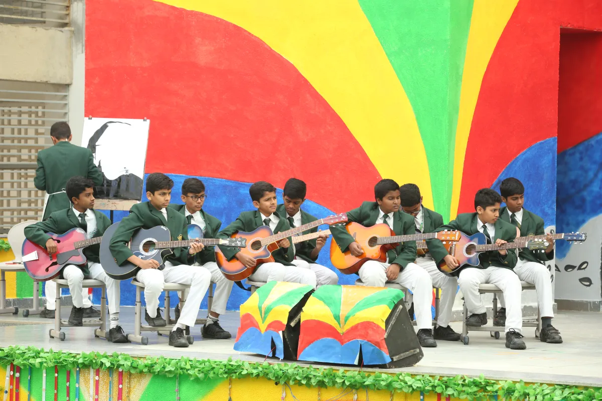 A group of students in DPS, Warangal school uniform playing guitar on the stage.
