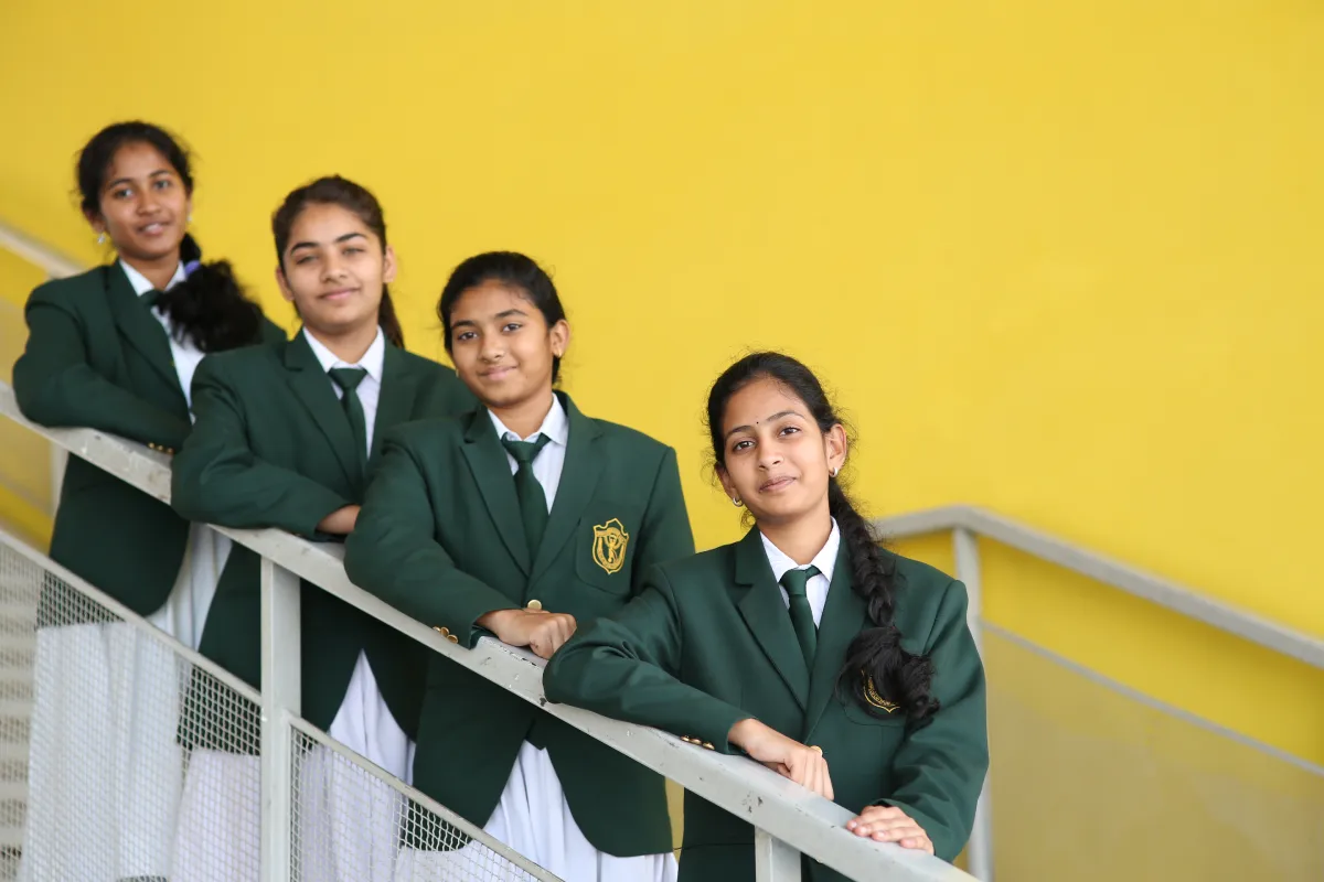 Four girls in school uniforms standing on the stairs at school.