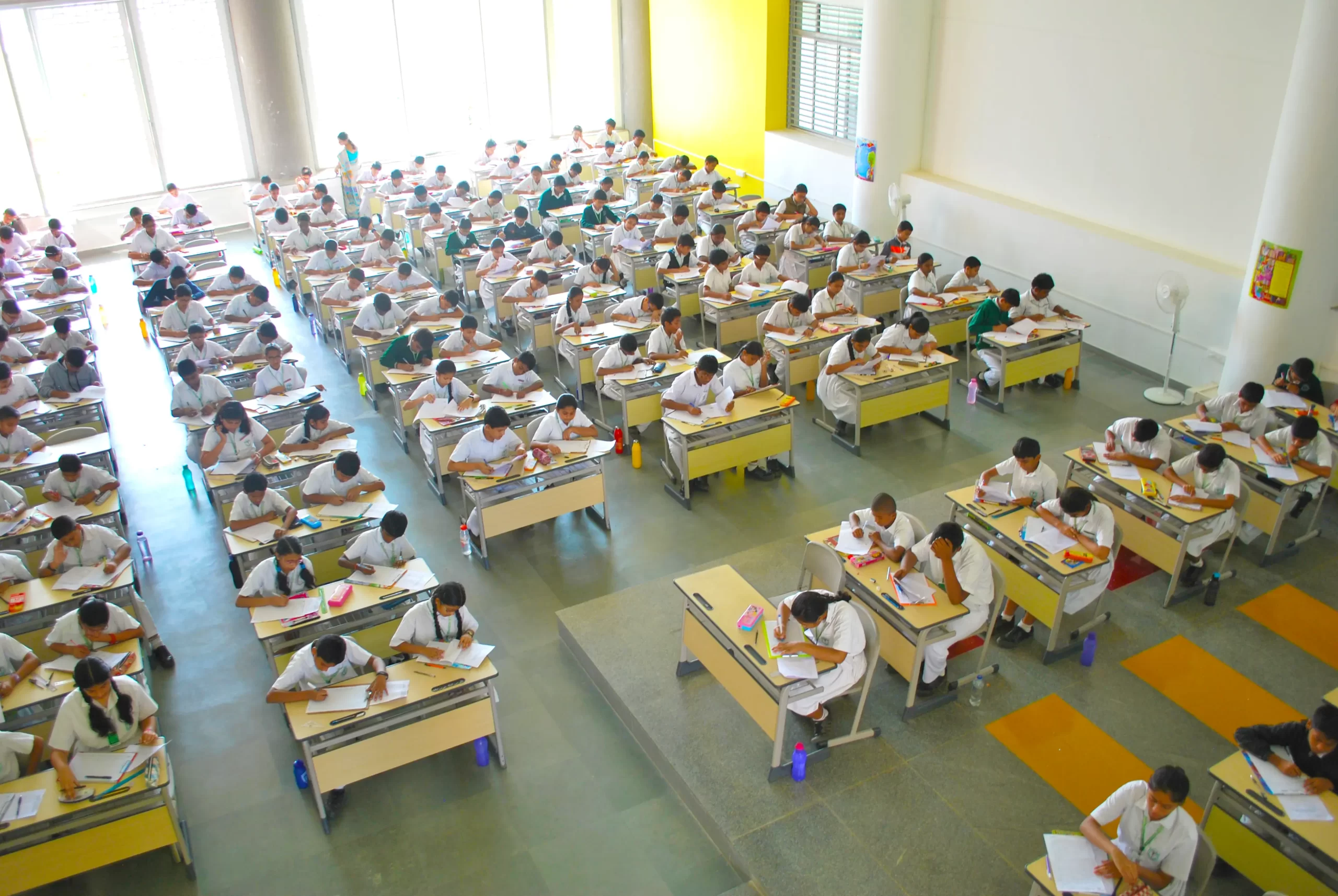 Students attempting their exam papers, while sitting in the examination hall.