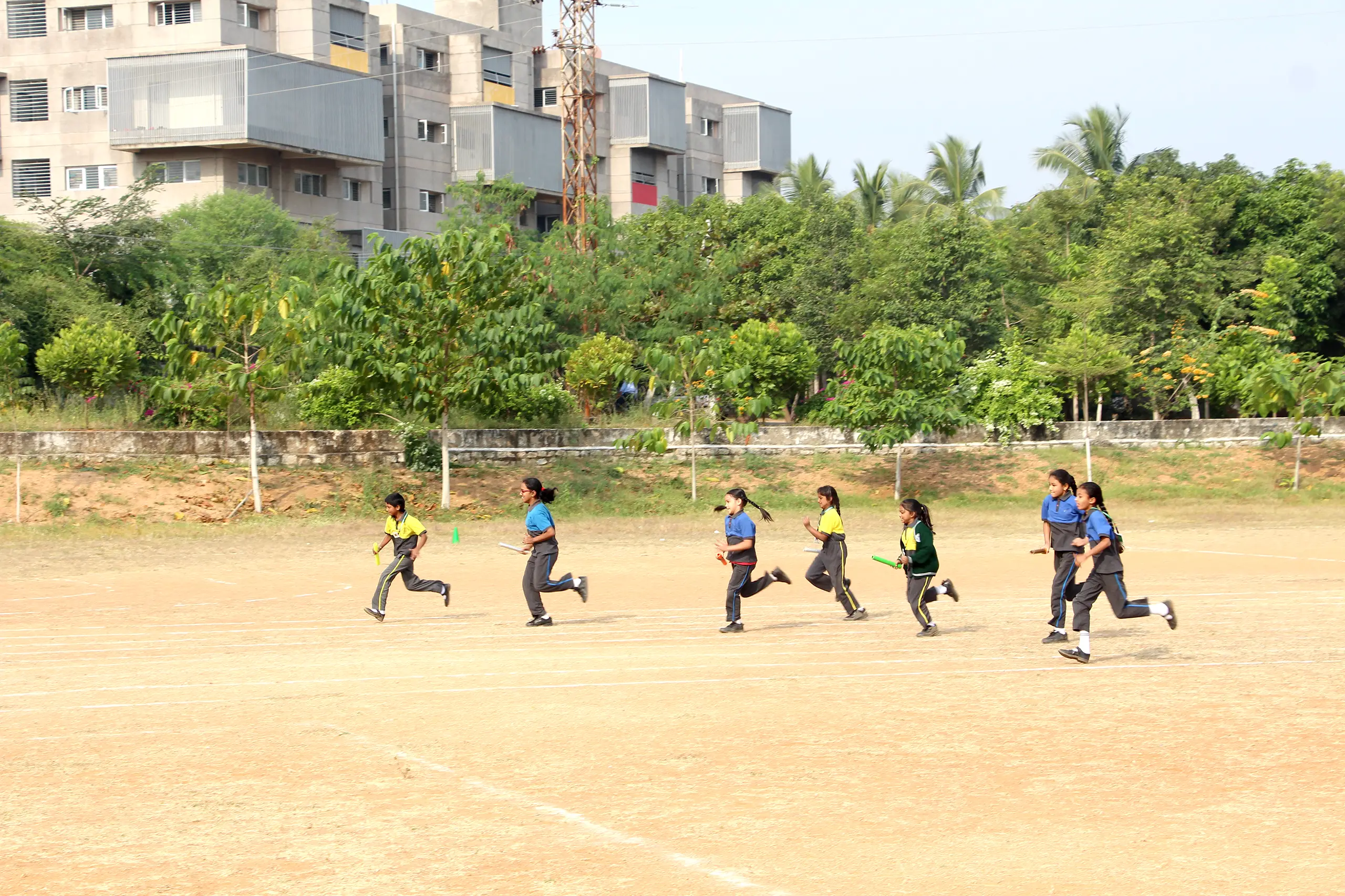 Children at DPS Warangal school playing in the ground with trees around.