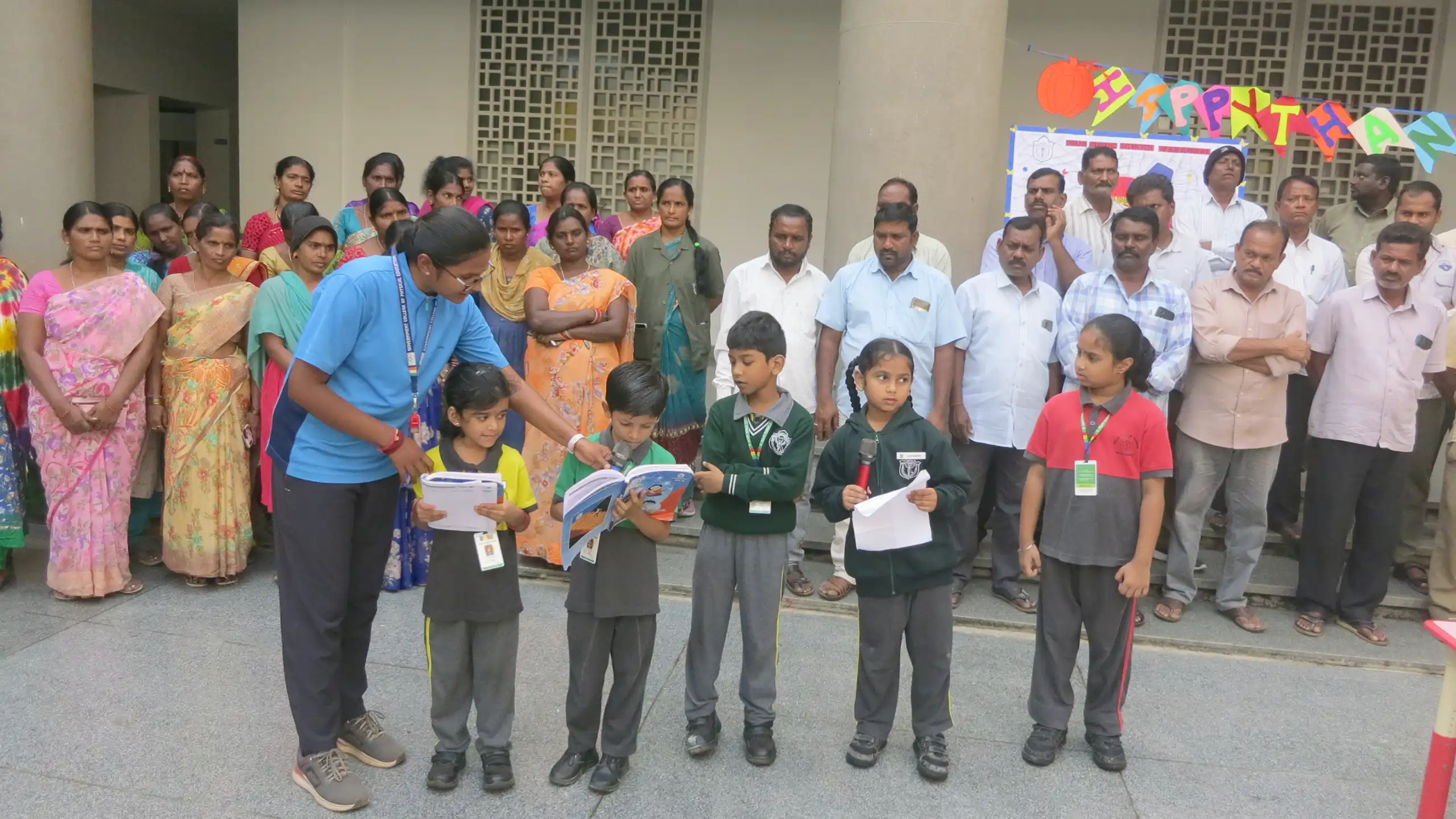 Students of DPS Warangal reading books and teacher assisting them during morning assembly.