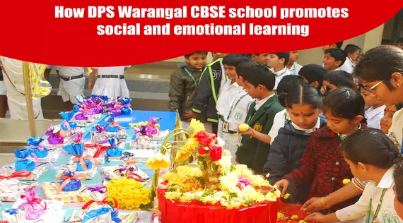 A group of children standing around a table full of gifts, at DPS Warangal