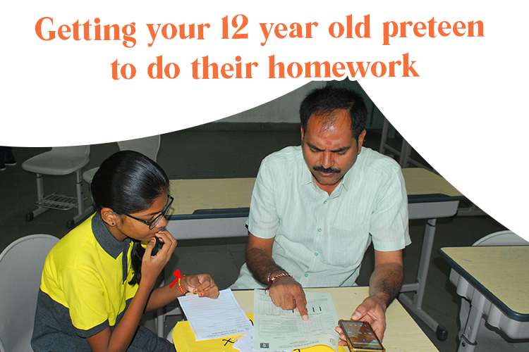 A teacher and kid sitting at a desk, helping to do their homework.