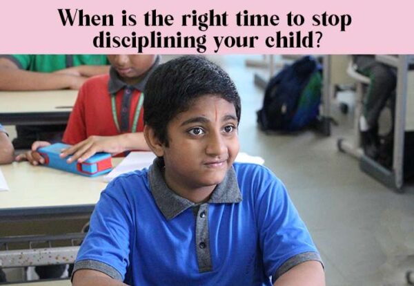 A child sitting at a desk and listening to the class. Text overlay: When is the right time to stop disciplining your child?