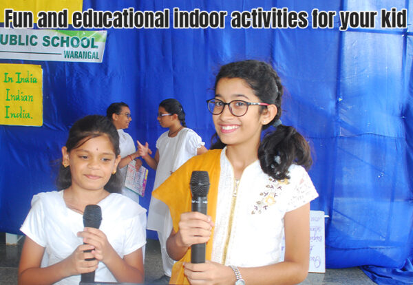 two young girls holding microphones in front of a blue backdrop telling about the importance of indoor games