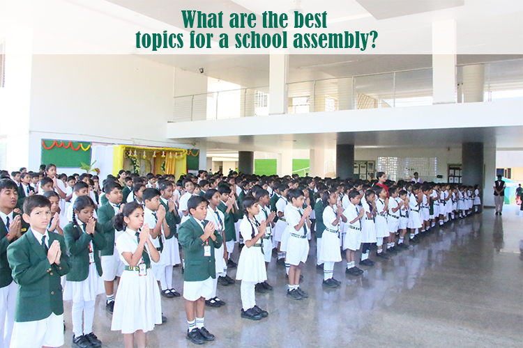 Students standing in rows with hands clasped, participating in a school assembly.