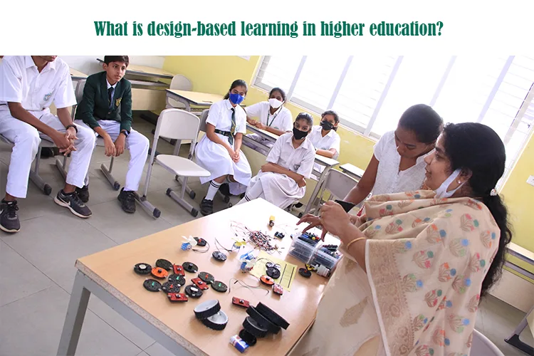 students in a classroom watching a presentation on a screen, with the teacher using a laptop, representing design-based learning in a digital classroom