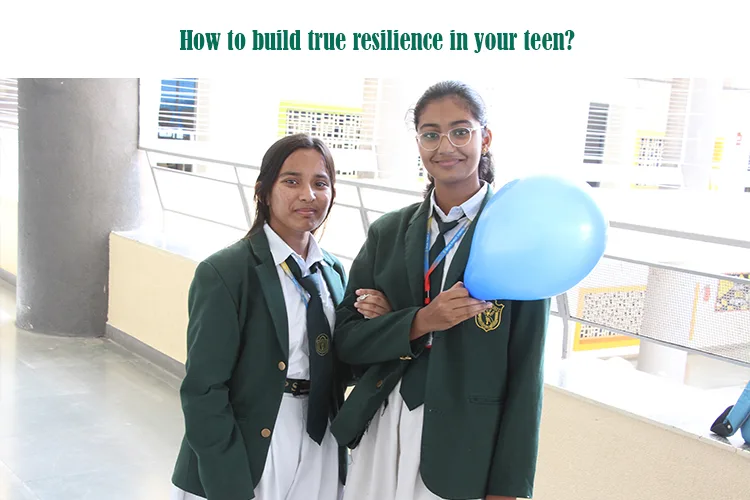 Two schoolgirls in green blazers and white uniforms stand together in a corridor, one holding a blue balloon, smiling softly at the camera.