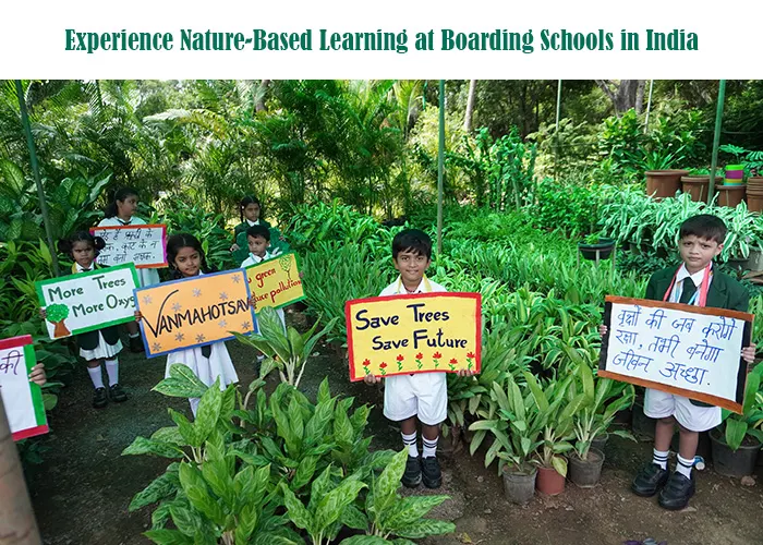 Students at a boarding school in India participating in a nature-based learning activity, holding “save trees” posters while surrounded by lush green plants in an outdoor garden